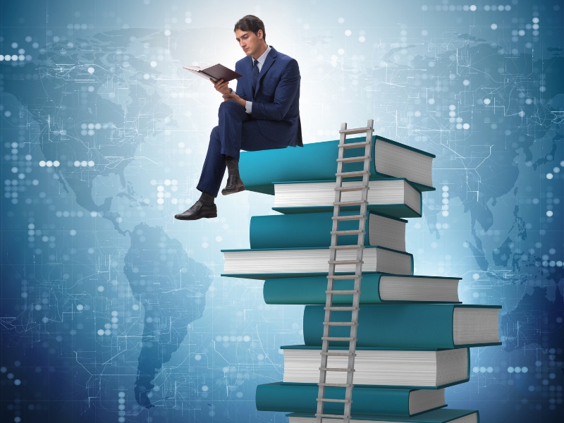 A man sits atop a large pile of books reading about SEO.